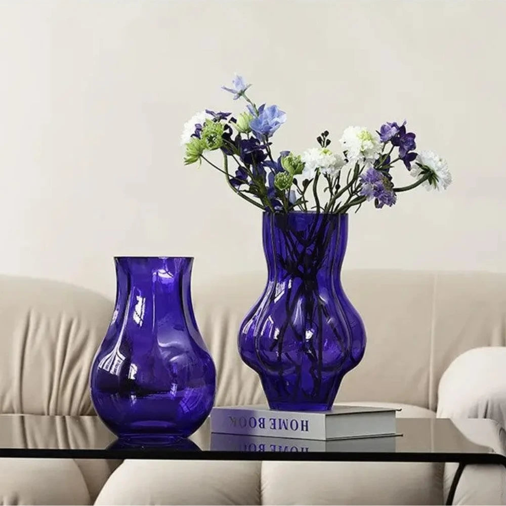 Two Purple Bud Vases with flowers inside on a coffee table