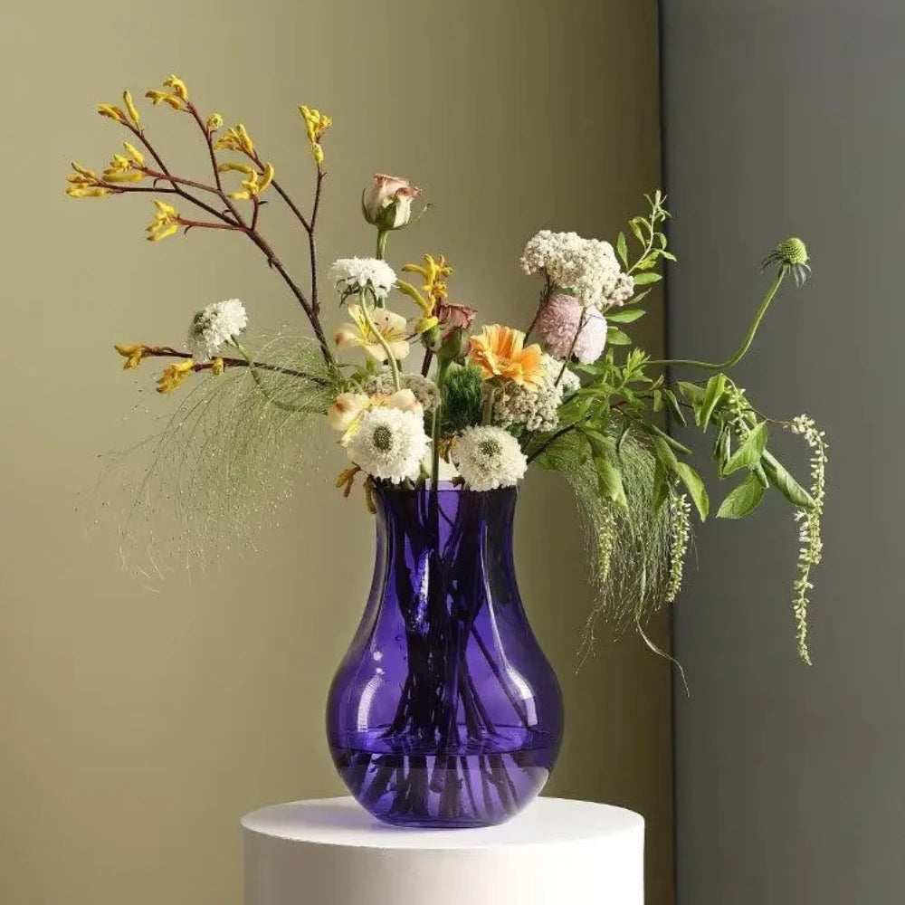 Purple Bud Vase with flowers inside on a white podium