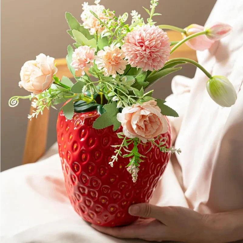 Person holding a Red Ceramic Vase with flowers inside