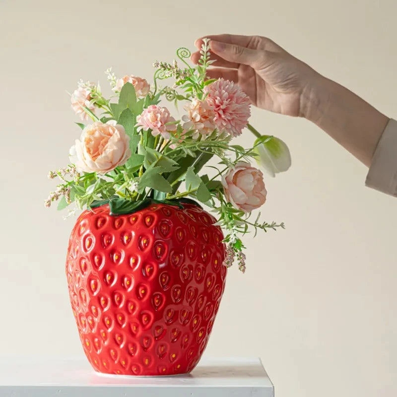 Person putting flowers into a Red Ceramic Vase 