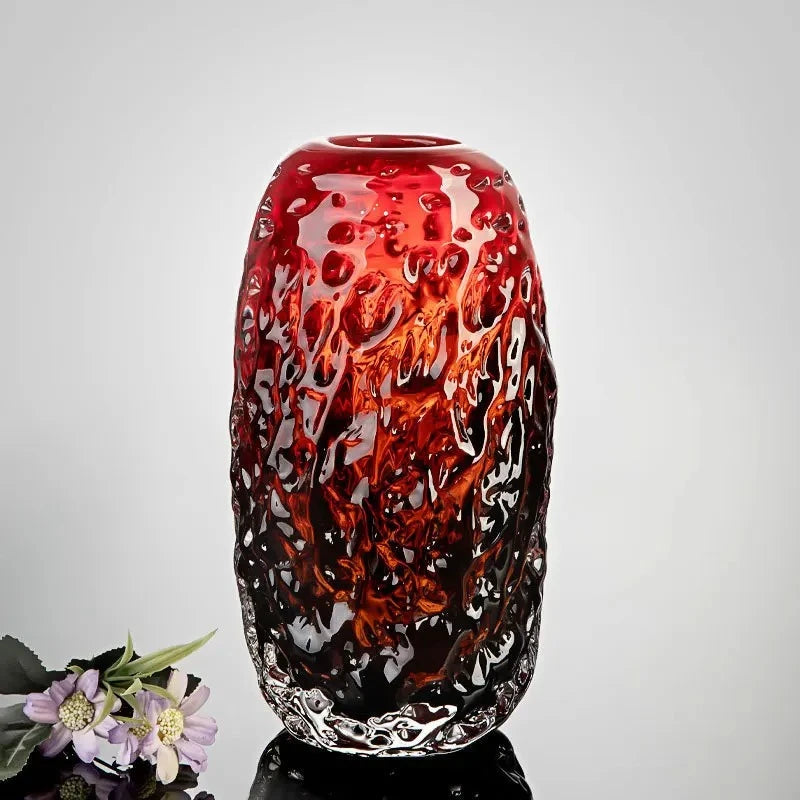 Large Red Glass Vase on a shiny surface next to flowers