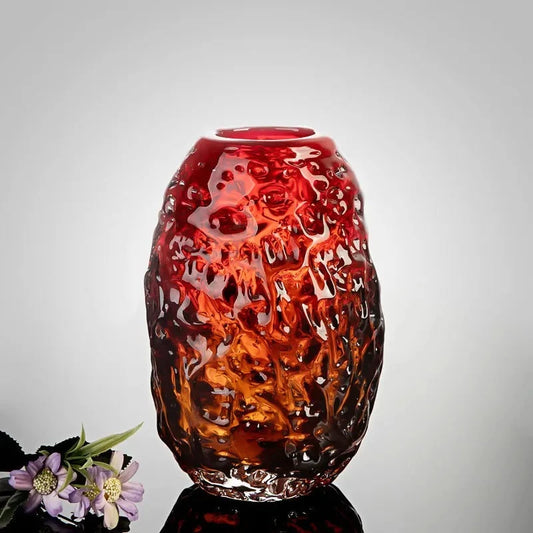 Red Glass Vase on a shiny surface next to flowers