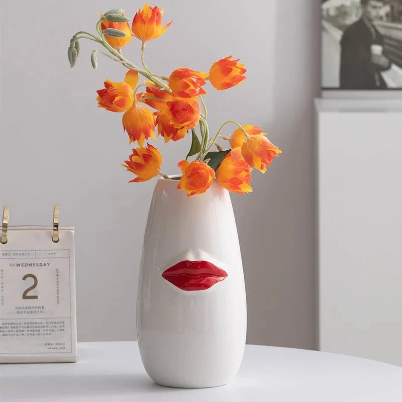 Red and White Vase with orange flowers inside standing next to a calendar