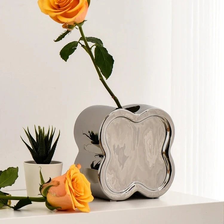 Silver Small Vase with an orange flower inside on a white dresser