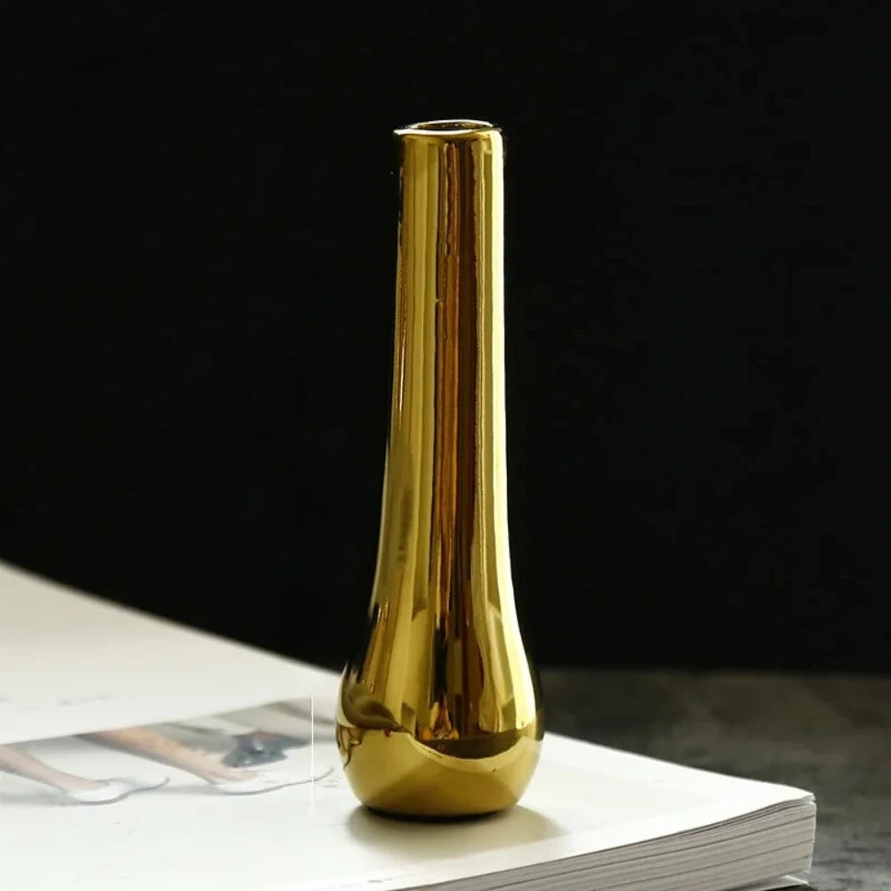 Slim Small Gold Vase on a white surface in front of a black background