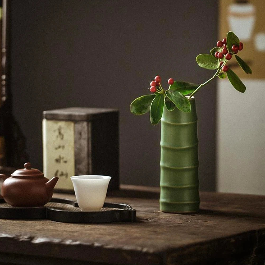 Small Green Vase on a wooden table next to decorational elements