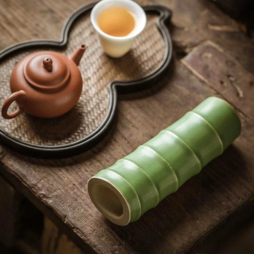 Small Green Vase laying sideways on a wooden table next to a can and mug 