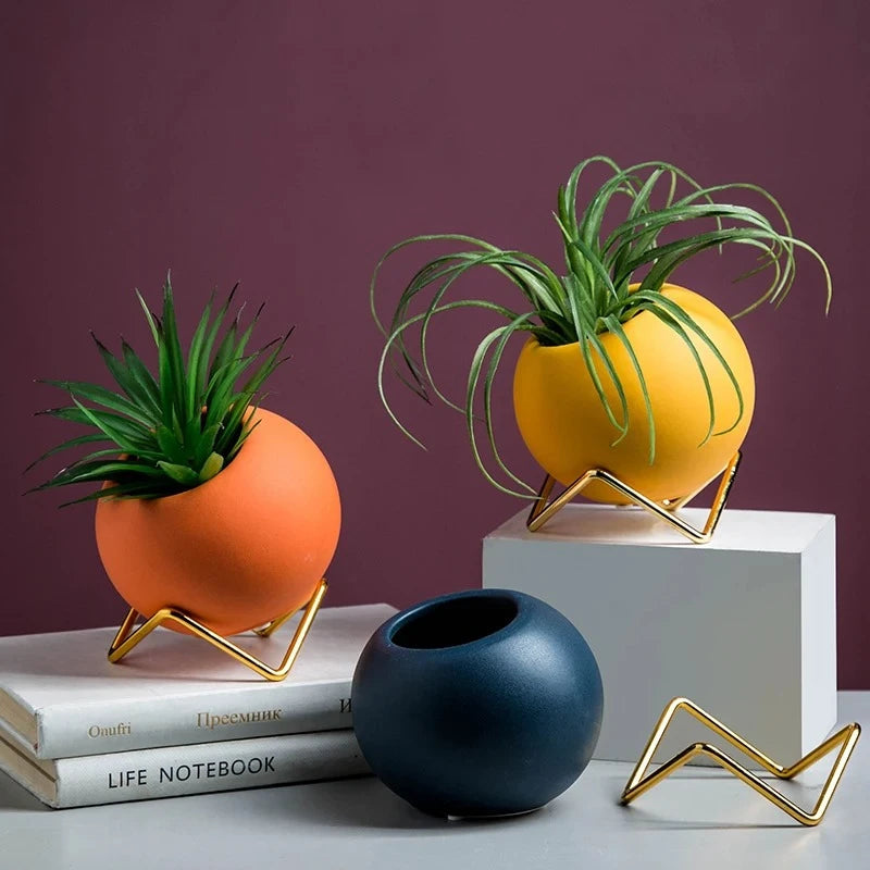 Three Small Round Vases on top of a stack of books in front of a wine red background