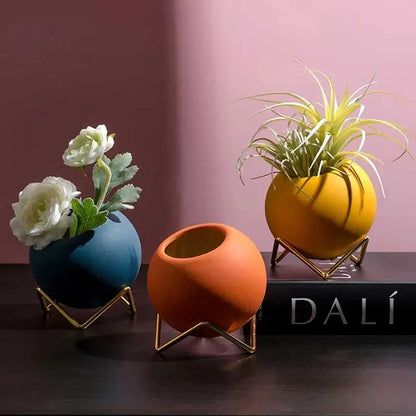 Three Small Round Vases on a black surface in front of a wine red background