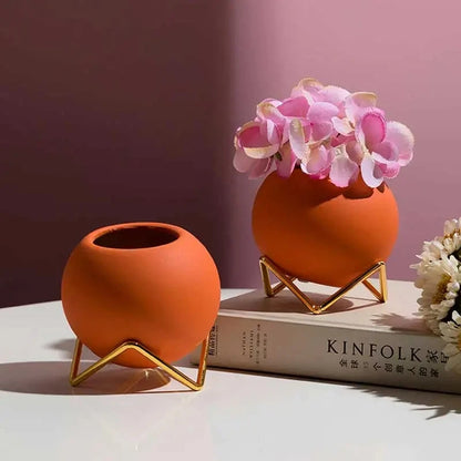 Two orange Small Round Vases on top of a book on a white surface