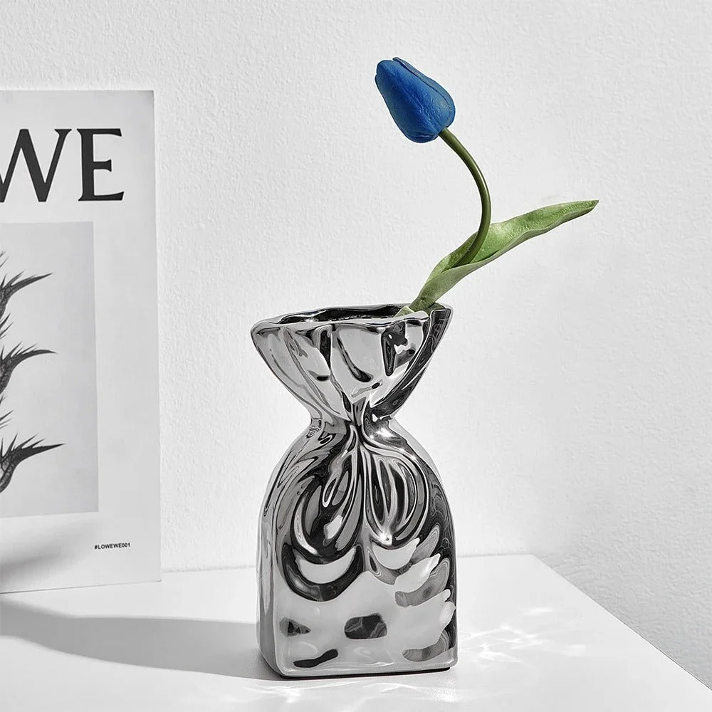 Small Silver Vase with a blue tulip inside next to a book on a table