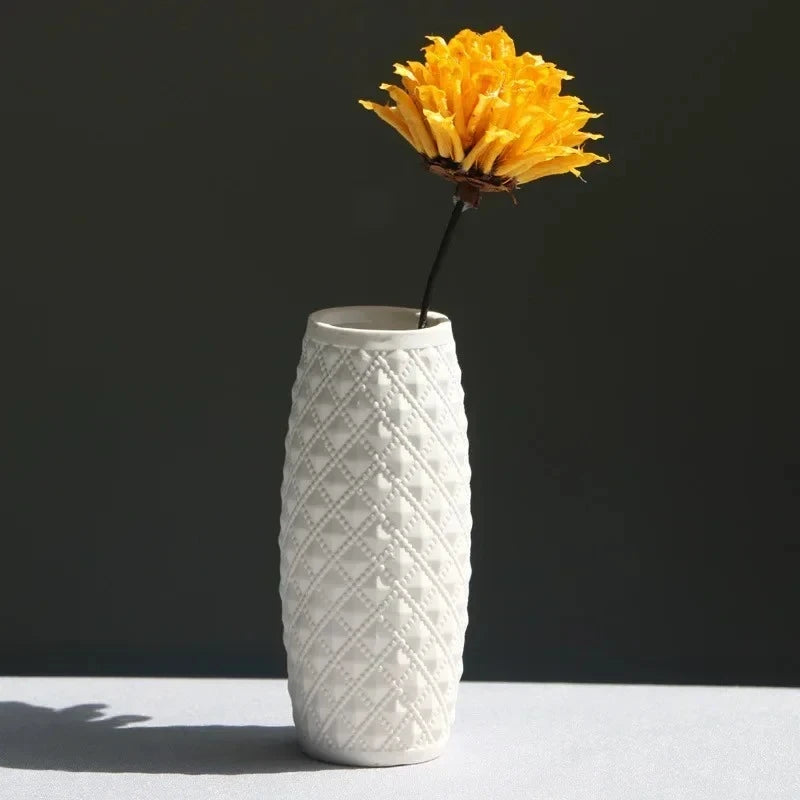 Small White Vase on a white surface with a yellow flower inside