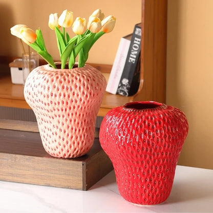 Two Strawberry Vases with flowers inside on a white marble table