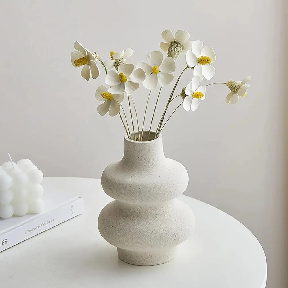 White Bud Vase with white daisy flowers inside on a white surface