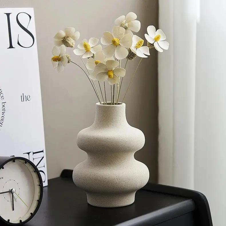 White Bud Vase with white flowers inside on a black surface