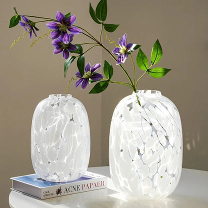 Two White Glass Vases on a white surface and flowers inside