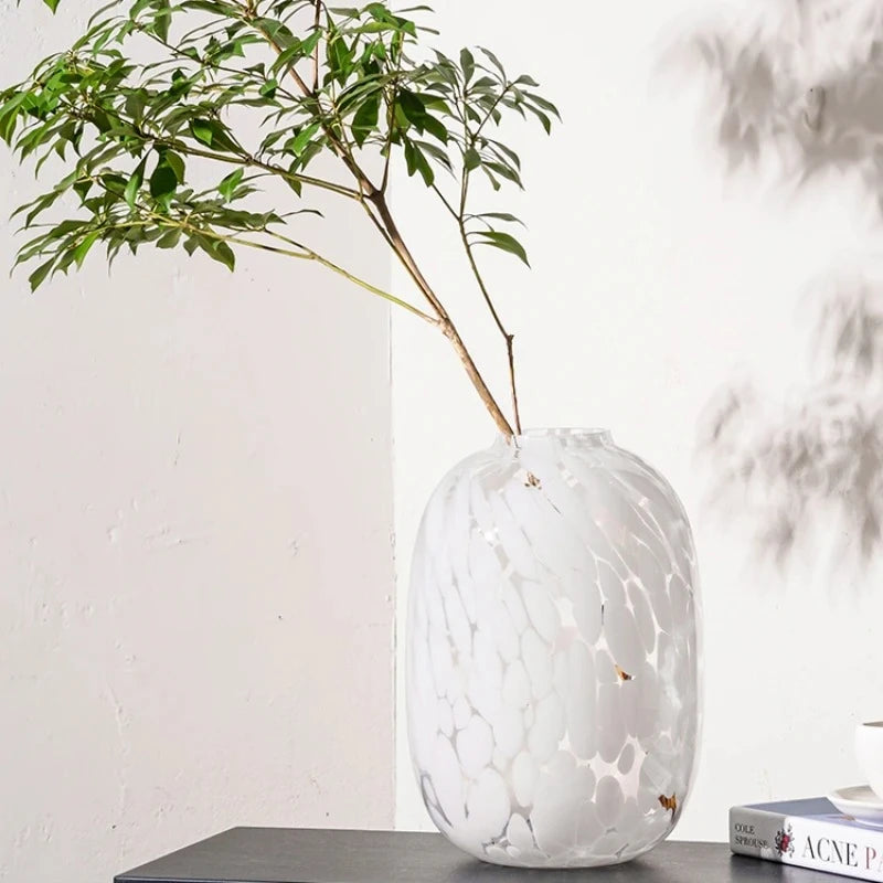 White Glass Vase with green fern inside on a gray table