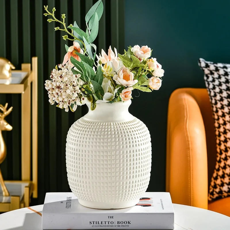 Plastic Vase in White with flowers inside standing on a book