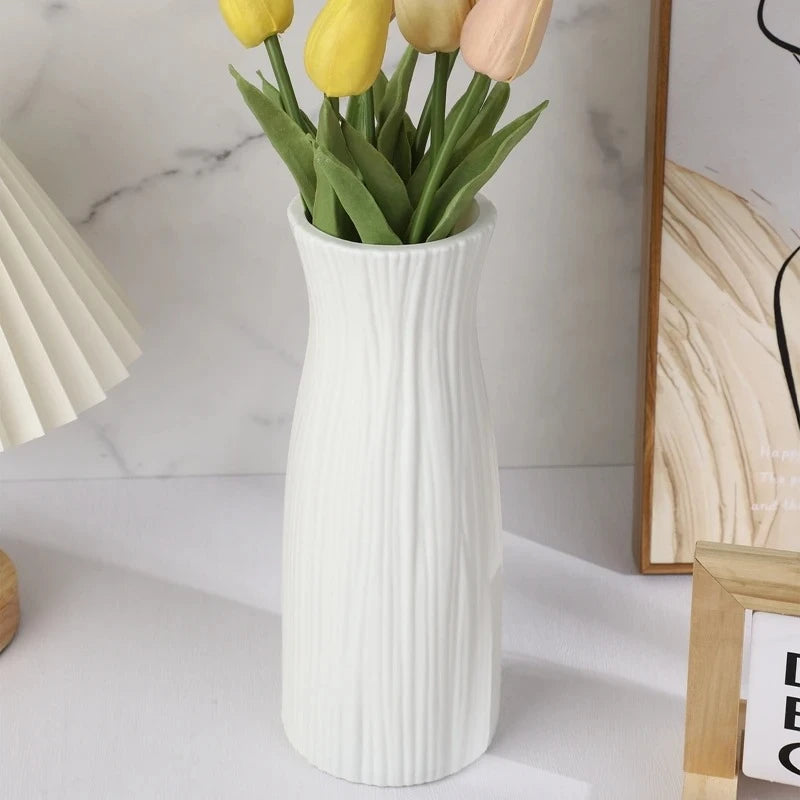 White Plastic Vase with yellow tulips inside next to an image frame