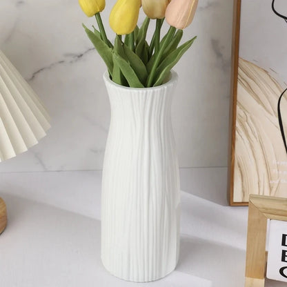 White Plastic Vase with yellow tulips inside next to an image frame