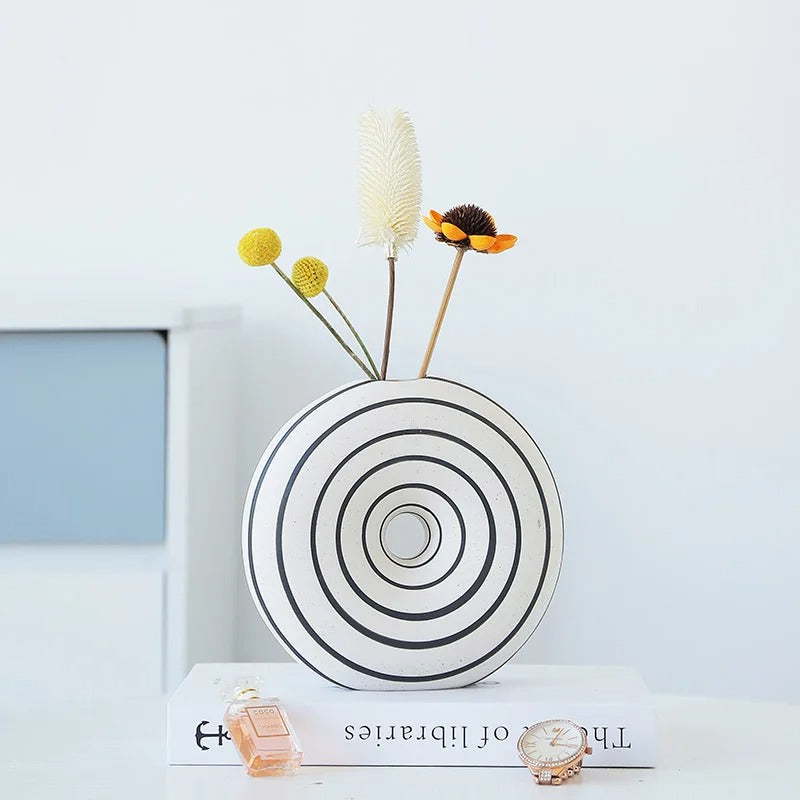 Medium sized White Round Vase standing on a decorative book in front of a shelf