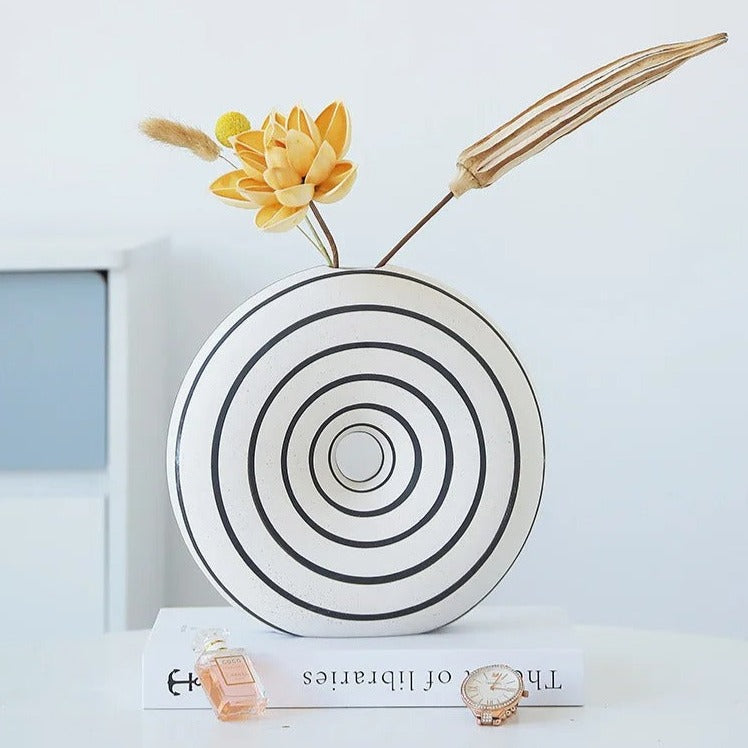 Large White Round Vase with decoration elements inside on top of a book