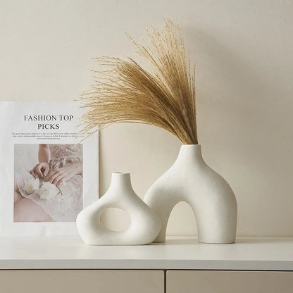 Two White Round Vases on a white surface with a book in the background